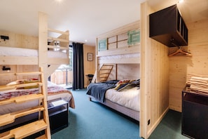 Une chambre avec des lits superposés, un bureau et un téléviseur fixé au mur.