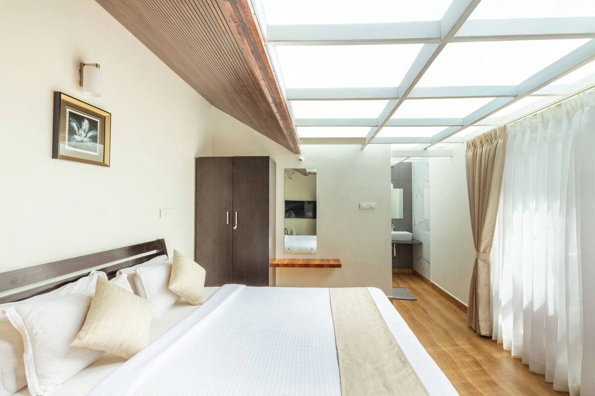 A bedroom with a large bed, a wardrobe, a bathroom, and a skylight.