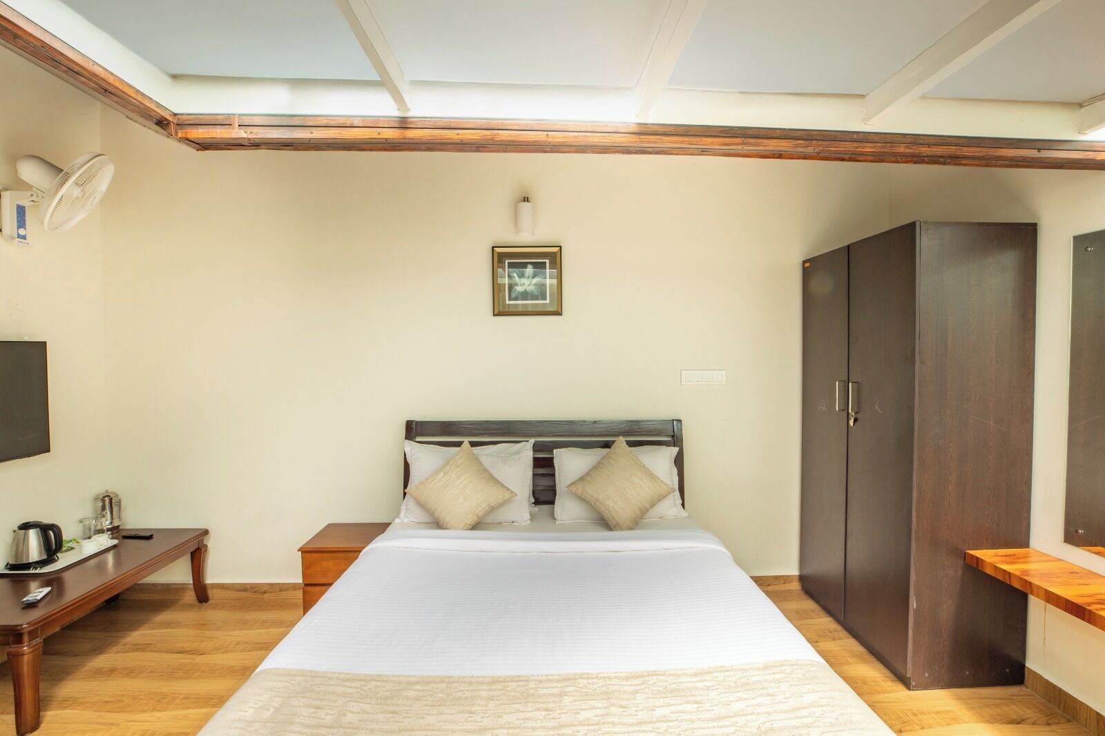 Un dormitorio con una cama grande, cabecera de madera, mesita de noche y un armario.