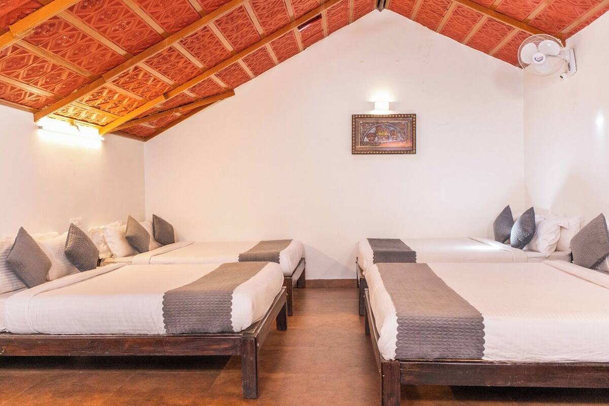 A room with two beds, a ceiling fan, and a framed picture on the wall.