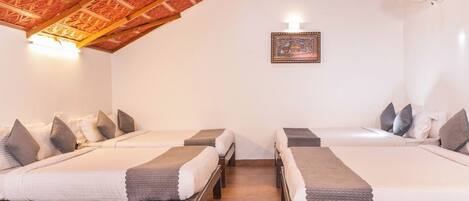 A room with two beds, a ceiling fan, and a framed picture on the wall.