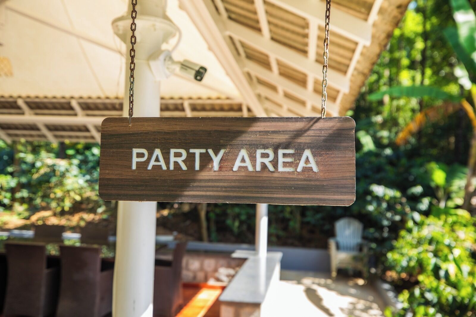 Une pancarte en bois portant l’inscription « ZONE DE FÊTE » est suspendue à une chaîne.