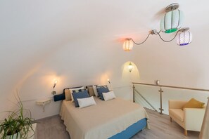 A bedroom with a bed, bedside tables, a nightstand, a potted plant, a sofa, and a balcony railing. - Casa Ivi | Panoramic Pool & Breathtaking View (Montepertuso)