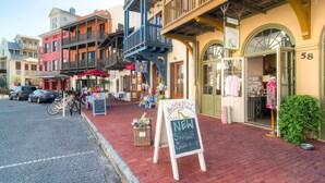 Una calle con un café al aire libre, una zapatería y una boutique.