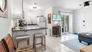 Una cocina moderna con armarios blancos, encimera de granito y una isla integrada con taburetes de bar.