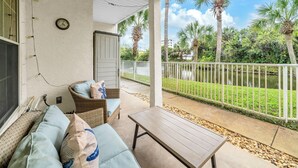 A covered patio with a sofa, a table, and a clock on the wall. - ☀️Walk to Beach | 4 Pools | Horizon South 59-104☀️ (Panama City Beach)