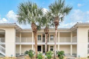 A two-story building with a balcony, palm trees, and a clear sky. - ☀️Walk to Beach | 4 Pools | Horizon South 59-104☀️ (Panama City Beach)