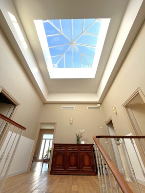 A spacious room with a skylight, wooden flooring, and a central wooden cabinet. - Villa ADELAIDA (Nice)