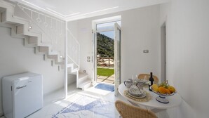 Un interior modern amb una escala, una zona de dinar amb taula per a dues persones i vista a l'exterior.