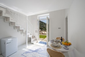A modern interior with a staircase, a dining area with a table set for two, and a view of the outdoors. - Casa Lucente - terrace sea view (Montepertuso)