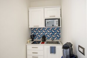 A compact kitchenette with a microwave, kettle, and sink. - Casa Lucente - terrace sea view (Montepertuso)