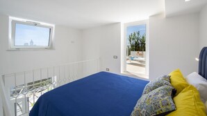 Un dormitori amb un llit, una finestra i un balcó amb vistes.