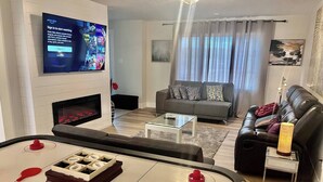 Un salon équipé d’un téléviseur à écran plat, d’une cheminée, d’un canapé, d’une table basse et d’une table de ping-pong.