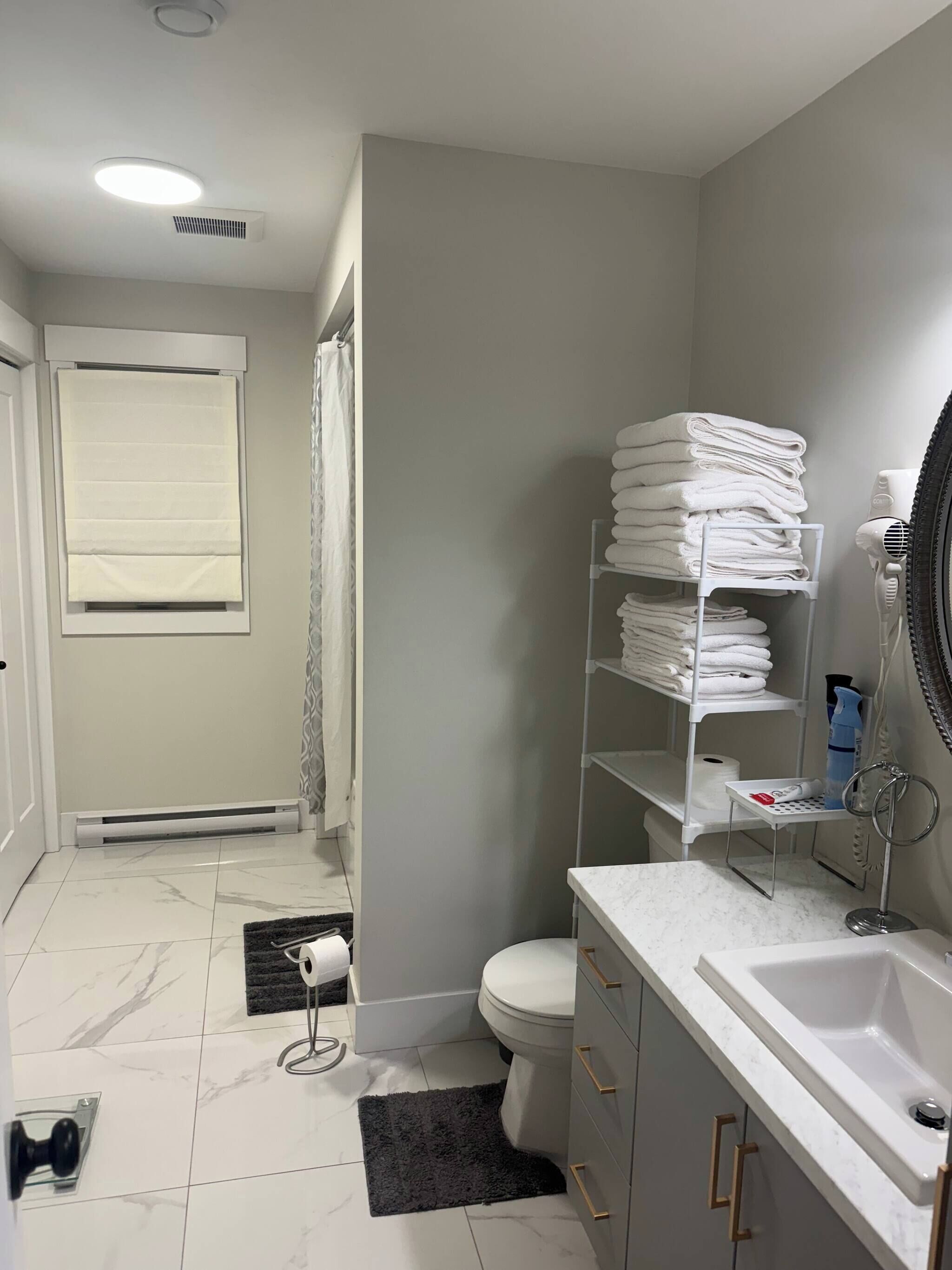 Un baño con inodoro, lavamanos, toallero y espejo.