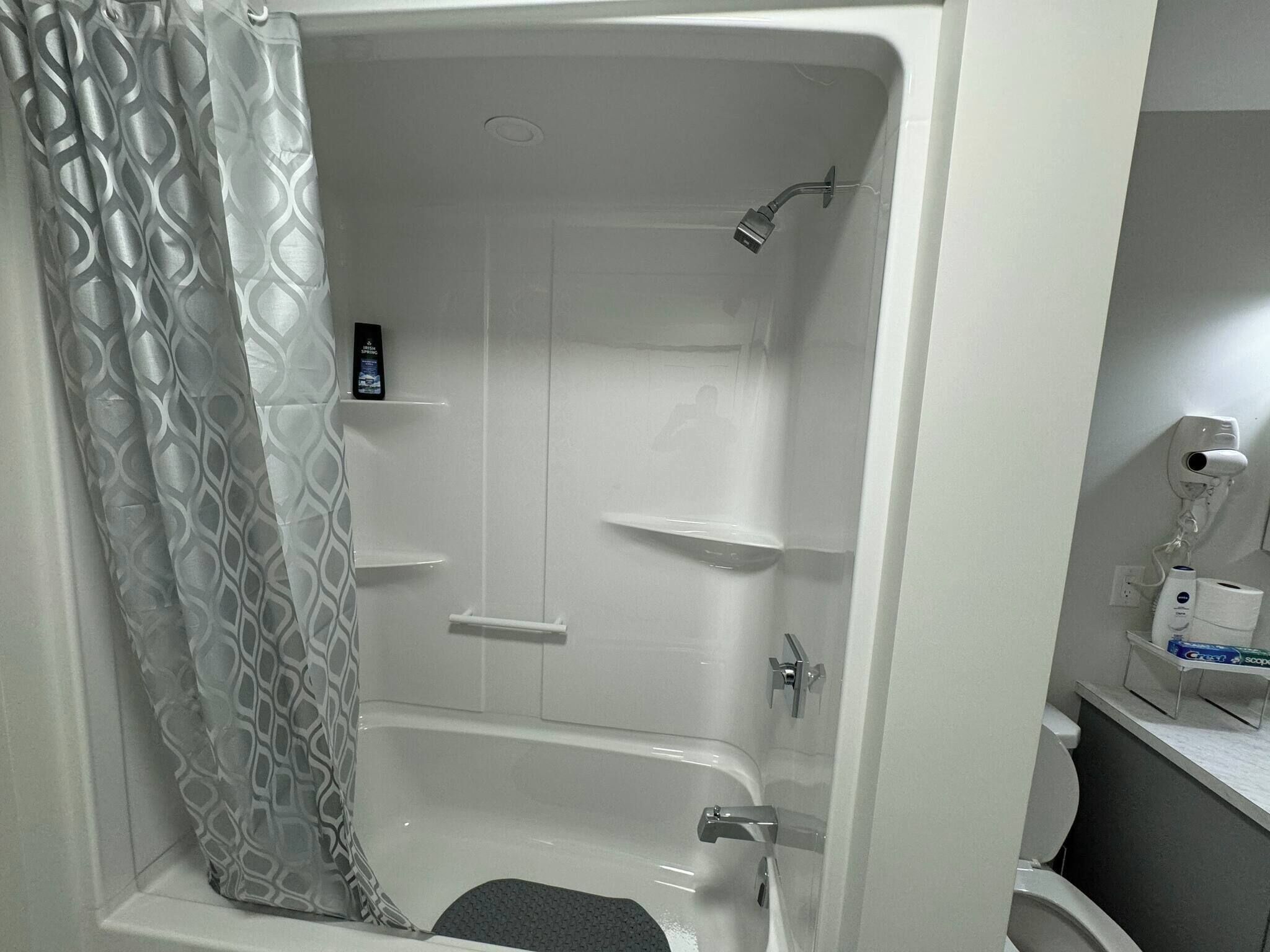 Une salle de bain avec une douche, des toilettes et un miroir.