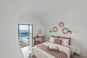 Une chambre à coucher avec un lit, une table de chevet, des éléments de décoration murale et une vue sur la mer.