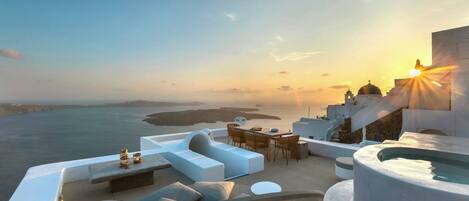A rooftop terrace with a pool, seating area, and a view of the sea and buildings.