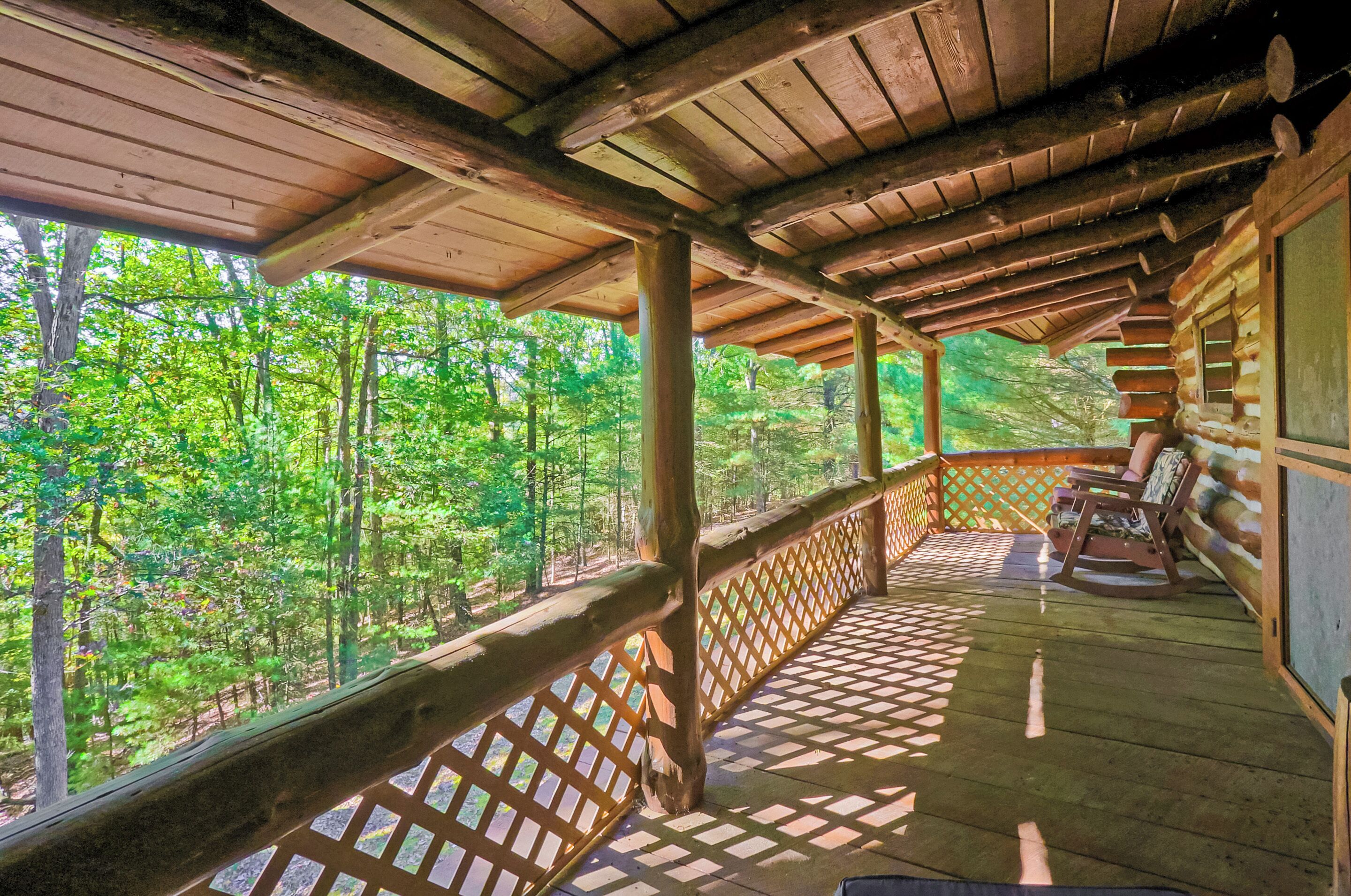 A wooden deck with a lattice railing overlooking a forest.