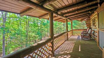 A wooden deck with a lattice railing overlooking a forest.