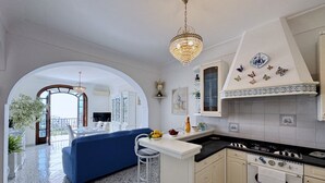 Cuina amb una illa central, un llumí i vista a un balcó exterior.