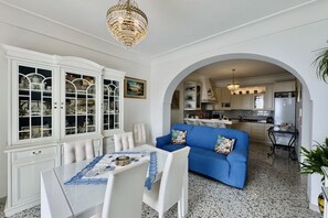 A dining area with a table and chairs, a blue sofa, and a kitchen visible through an archway. - Casa Malisa - Terrace sea view (Positano)