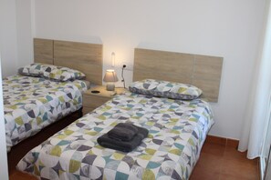 Ein Hotelzimmer mit zwei Betten, jedes mit einer gemusterten Tagesdecke, einer Nachttischlampe und einem Nachttisch.