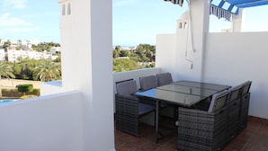 En terrasse med et bord og stole, udsigt over byen og flisegulv.