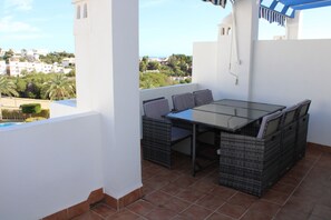 Eine Terrasse mit Tisch und Stühlen und Blick auf die Stadt, außerdem ein Fliesenboden.