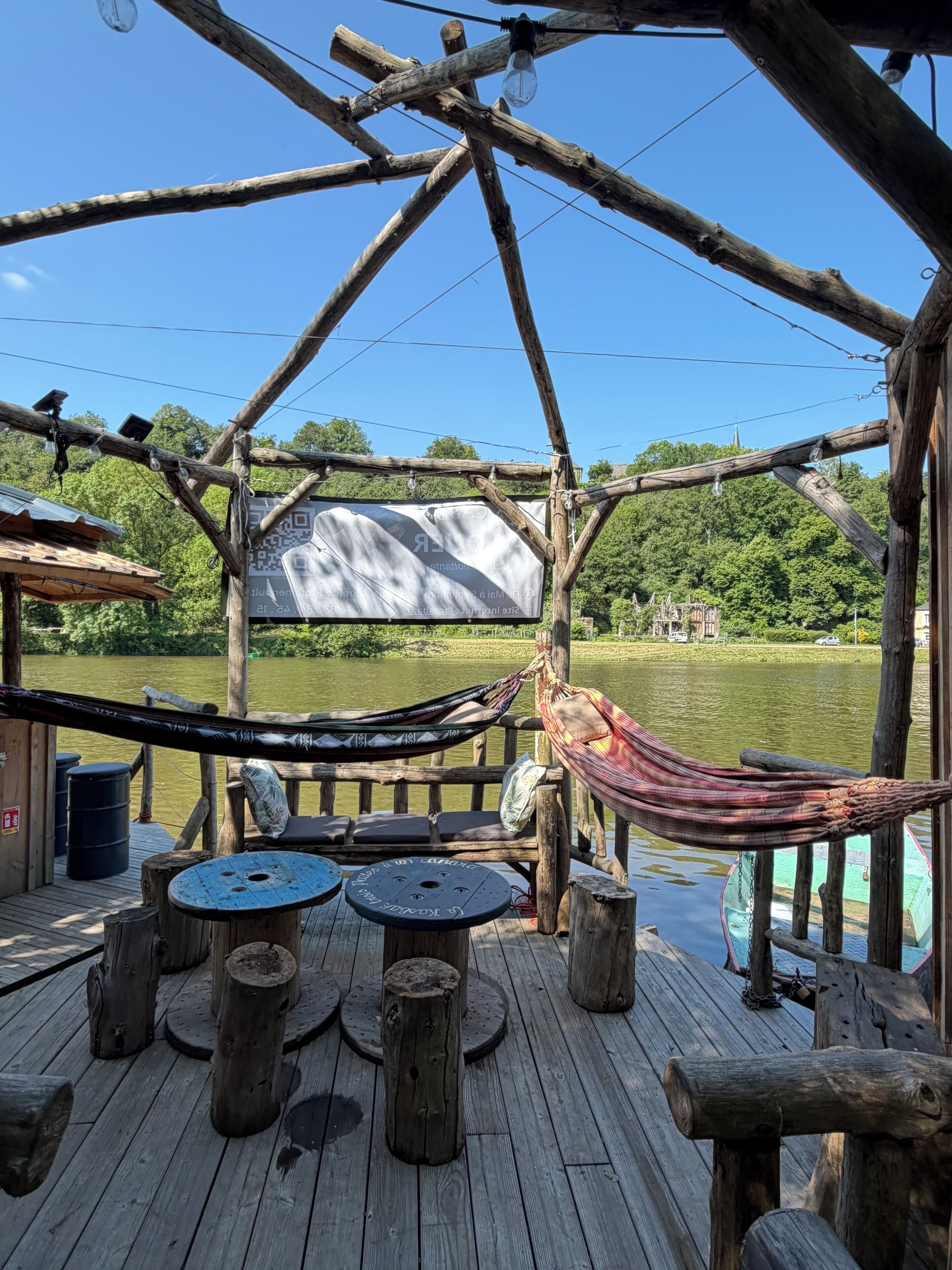 Une terrasse en bois avec un hamac, une table et un banc.