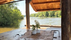 Una terraza de madera con vistas a un río y árboles.