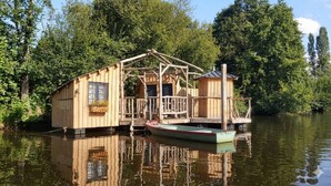 Una estructura flotante de madera con un muelle, rodeada de agua y árboles.