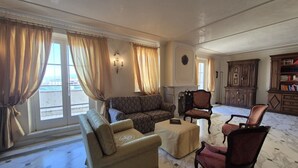 Ein geräumiges Wohnzimmer mit einer Couch, Sesseln, einem Couchtisch und einem Kamin.