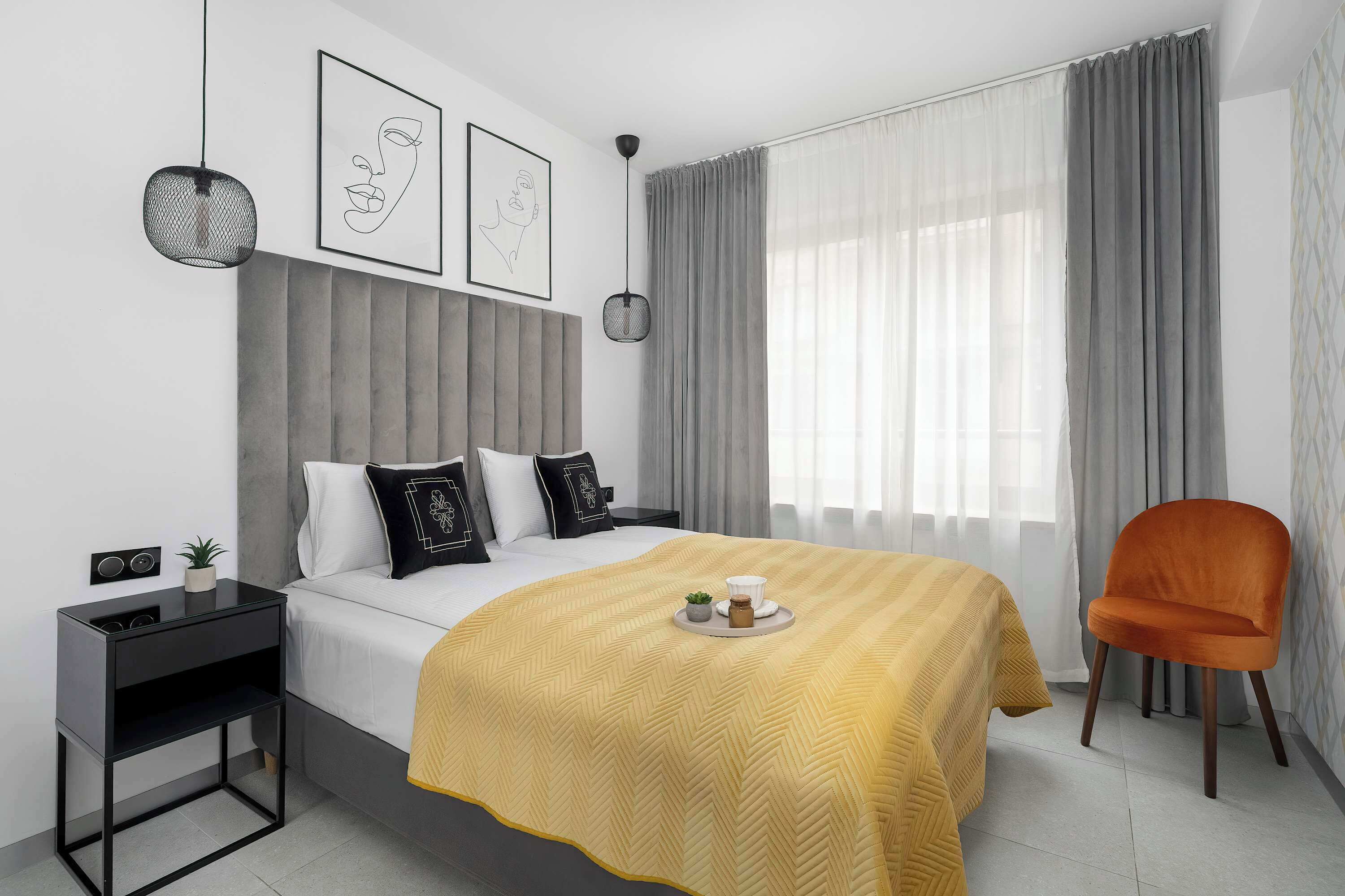 A modern bedroom with a bed, bedside table, chair, and artwork on the wall.