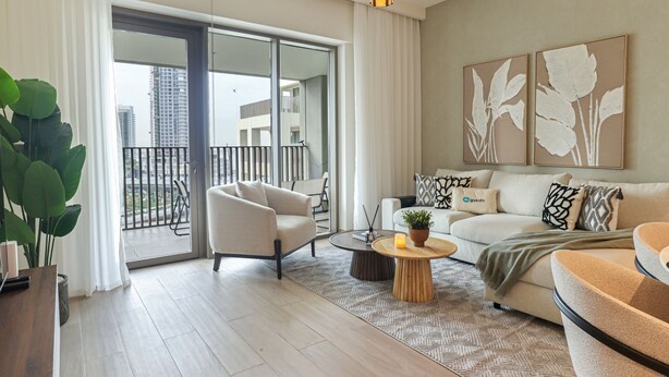 A modern living room with a sofa, armchair, coffee table, and a potted plant. - 2BR  Apt in Dubai Creek Grove 3 (Dubai)