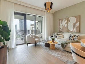 A modern living room with a sofa, armchair, coffee table, and a potted plant. - 2BR  Apt in Dubai Creek Grove 3 (Dubai)