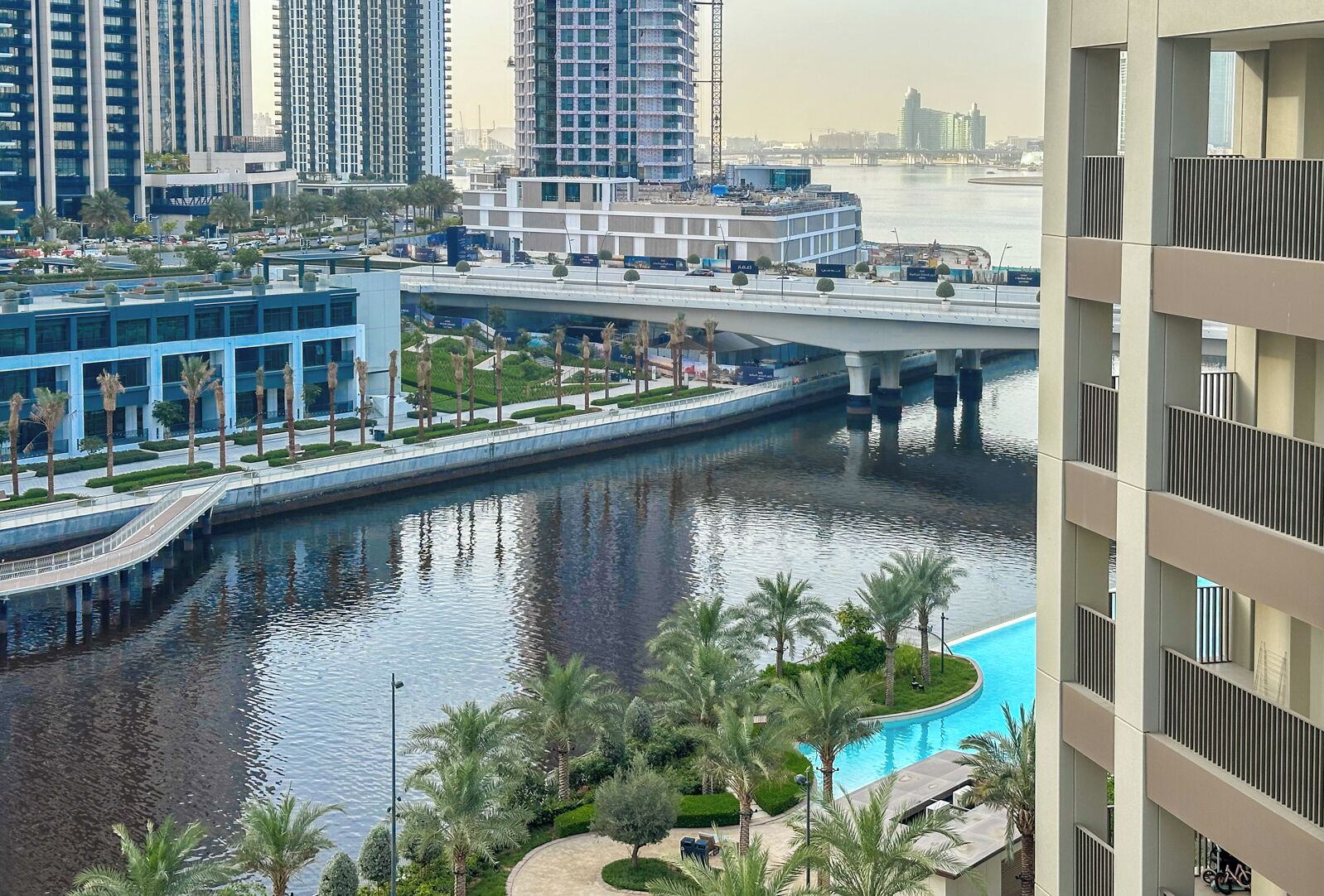 A modern urban area with high-rise buildings, a bridge, a canal, and a swimming pool.