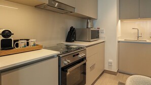 A compact kitchenette with a gas stove, oven, microwave, and a coffee machine. - 2BR  Apt in Dubai Creek Grove 3 (Dubai)