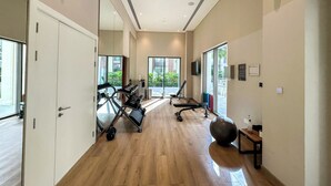 A gym with exercise equipment, large windows, and a wooden floor. - 2BR  Apt in Dubai Creek Grove 3 (Dubai)