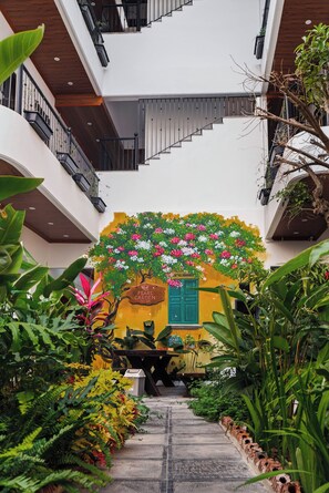 A multi-level building with a staircase, a green door, and a mural of a tree with flowers. - Pearl Garden Tam Coc (Hoa Lư)