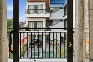 A multi-story building with balconies, a swimming pool, and a dining area visible through a gate. - Pearl Garden Tam Coc (Hoa Lư)