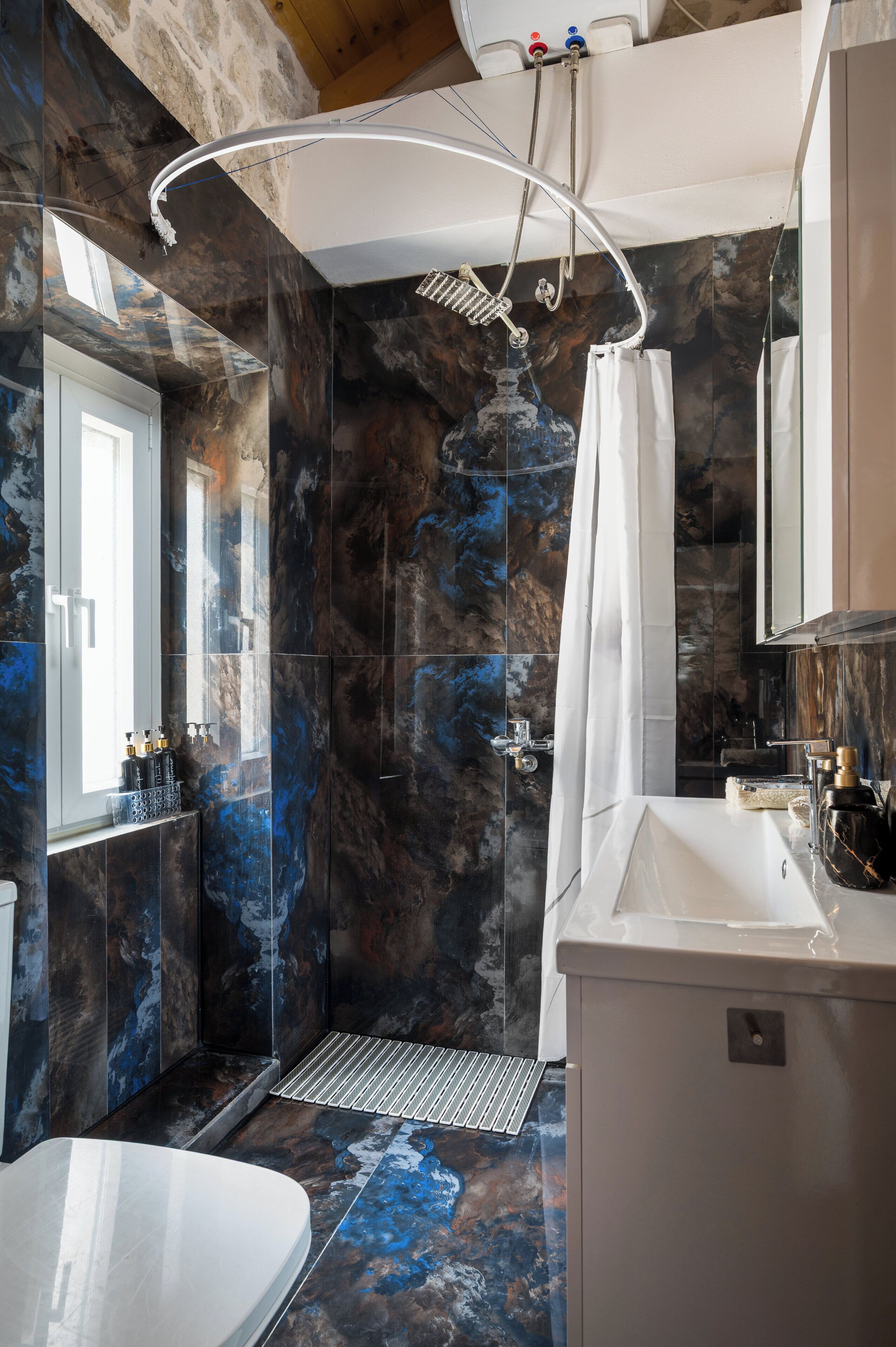 A bathroom with a shower, a sink, and a mirror.