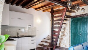 A kitchen with white cabinets, a sink, and a staircase leading to a green door. - Art House with Seaview by Konnect, Spartylas (Corfu)