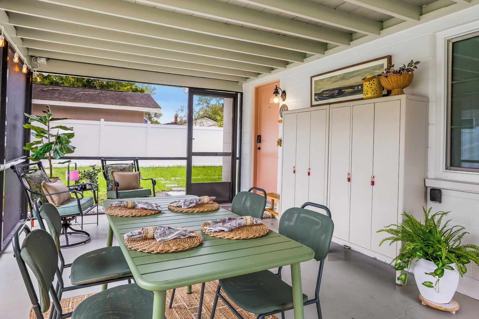 A covered patio with a table set for four, surrounded by chairs, and a storage unit with cabinets.