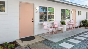 Edificio a un piano con facciata bianca, numero 617, dotato di ingresso, due finestre e un piccolo portico con sedie rosa e un tavolo.