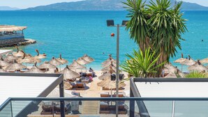 A balcony with a view of the sea, lounge chairs, and a table. - Vila Era Beach 2 (Sarande)