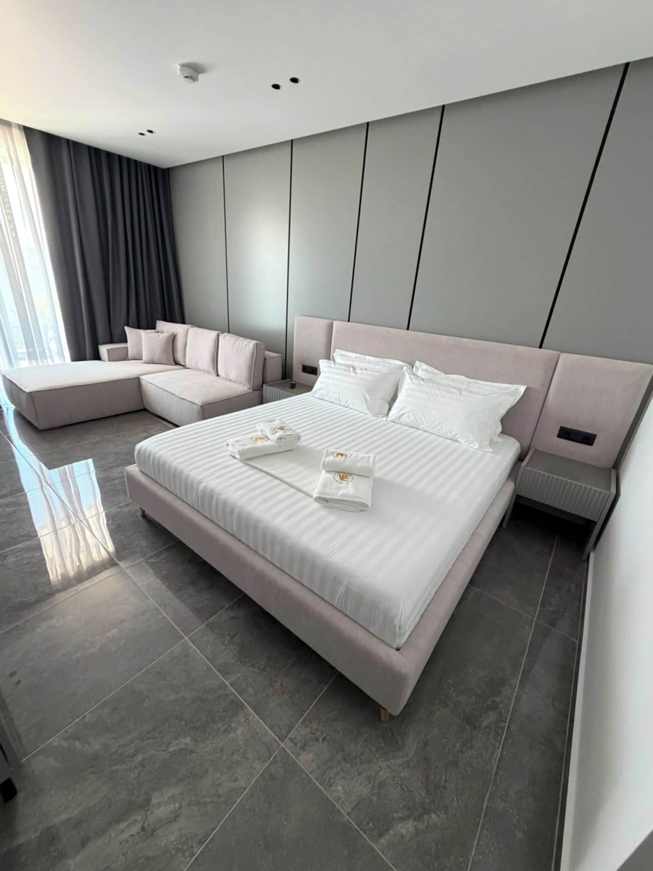 Un dormitorio moderno con una cama grande, un sofá y una mesita de noche.