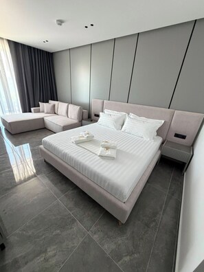 Un dormitorio moderno con una cama grande, un sofá y una mesita de noche.