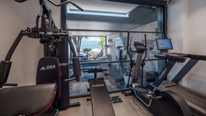 A modern gym with exercise equipment, a treadmill, and a large window overlooking a scenic outdoor area. - Vila Era Beach 2 (Sarande)
