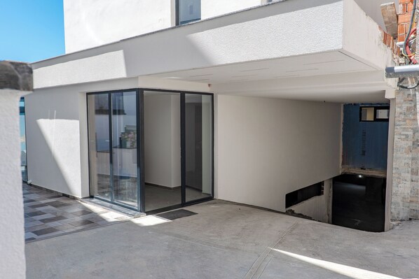 A modern building with a glass door entrance, a visible staircase, and a blue door in the background. - Vila Era Beach 2 (Sarande)