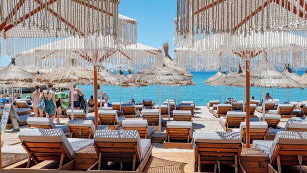 A beachside resort with wooden lounge chairs, thatched umbrellas, and a clear view of the sea. - Vila Era Beach 2 (Sarande)